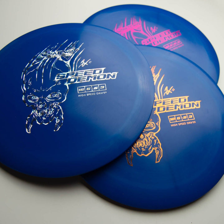 Three Speed Demon - Cobalt distance driver discs display stylized skull graphics in white, pink, and orange on blue and purple backgrounds, arranged in an overlapping layout on a white surface.
