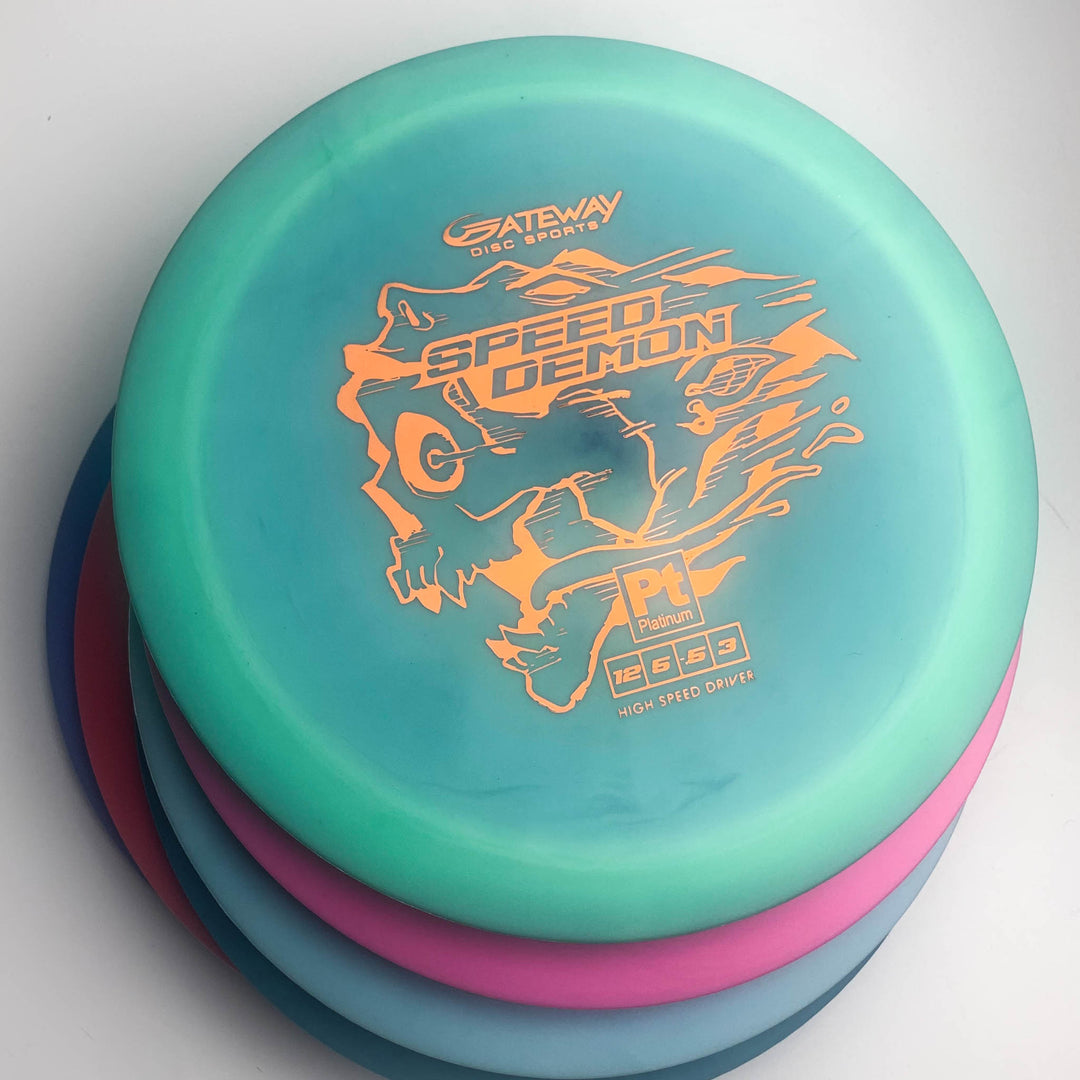 Four stacked disc golf discs, with the top teal disc showing orange "Speed Demon - Platinum" branding from Gateway Disc Sports—an overstable distance driver designed for powerful forehands and booming backhand flex shots.