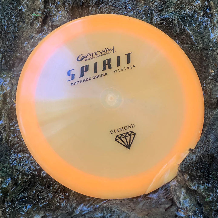 An orange Spirit - Diamond high speed overstable driver by Gateway with a chipped edge rests on a wet, textured surface.