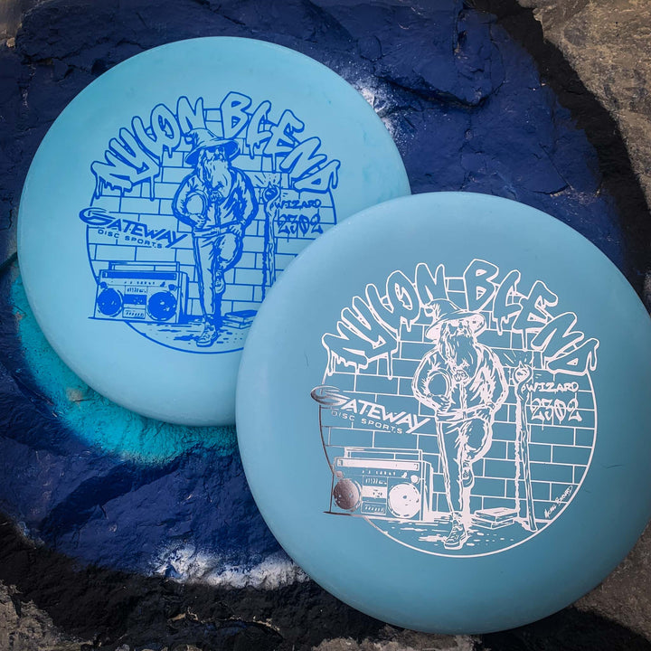 Two blue "Wizard - Suregrip Nylon" disc golf discs featuring an illustrated figure with a boombox. These stable putters rest on painted concrete, ideal for reliable mid-range drives.