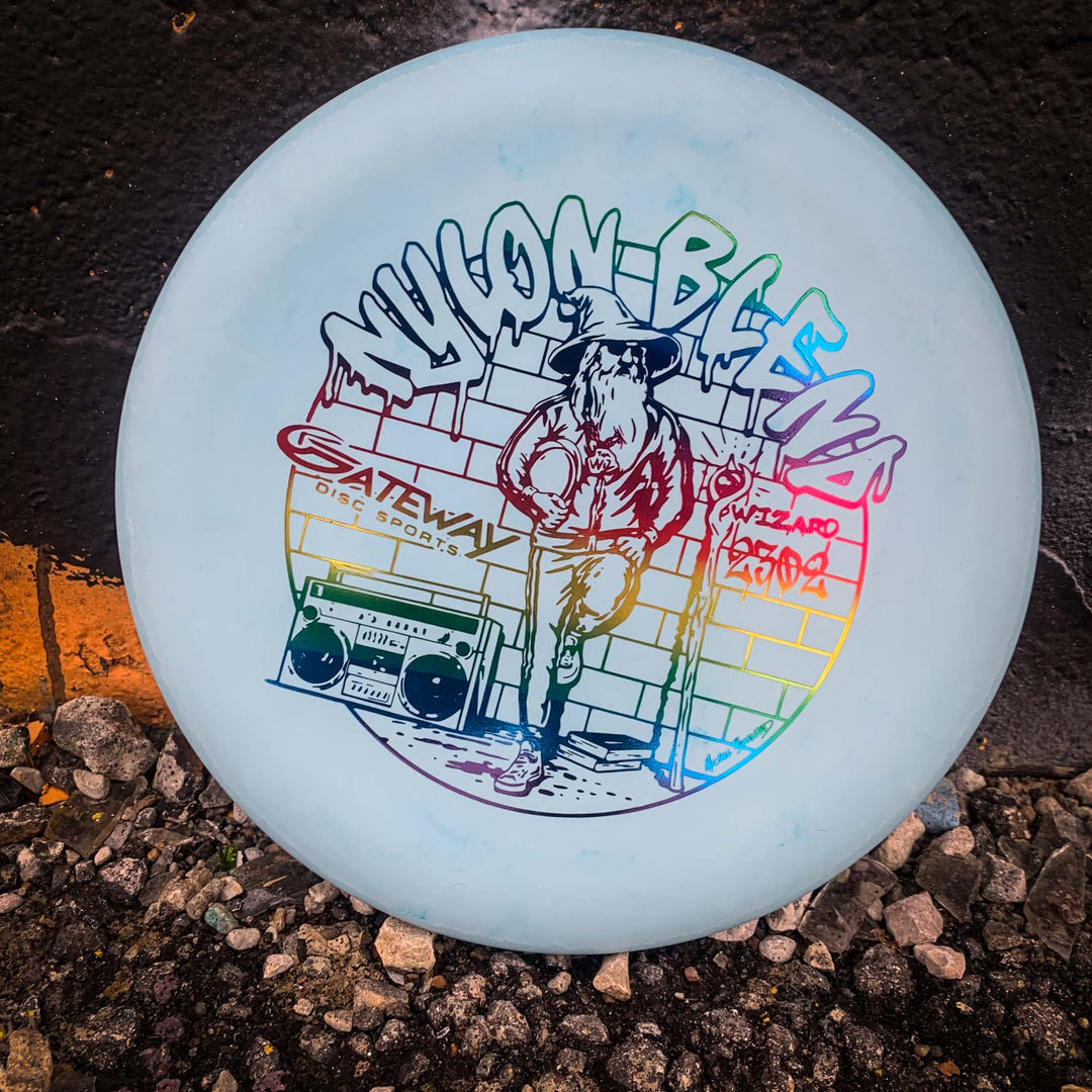 The Wizard - Suregrip Nylon is a white stable putter disc featuring colorful artwork of a wizard with a staff and boombox, leaning on a wall. —Gateway Disc Sports—� and —Wizard—� appear in graffiti-style—ideal for putts or accurate mid-range drives.