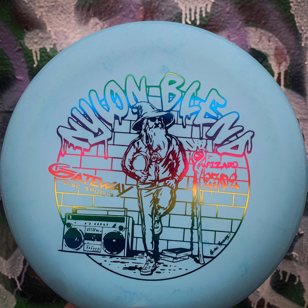 The Wizard - Suregrip Nylon is a light blue disc showing the Wizard holding a disc by a boombox in front of graffiti-style "WIZARD" and "Yoonblend" text—ideal for mid-range drives or anyone needing a stable putter.