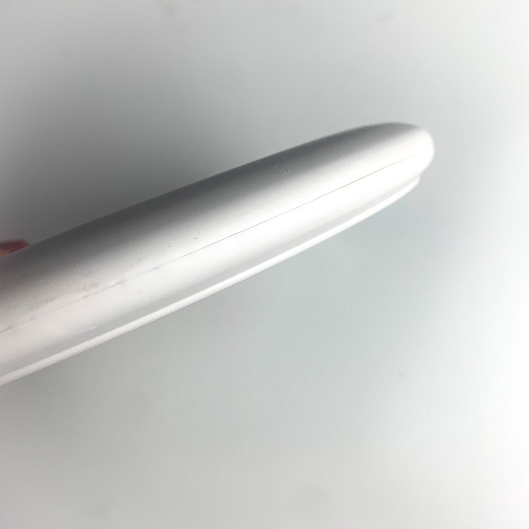 Close-up of the smooth, white edge of a Wizard Leaf Suregrip Putter by Gateway Disc Sports, its shape reminiscent of the iconic leaf design, set against a plain white background.