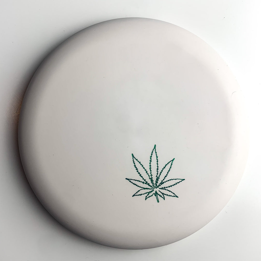 The Wizard Leaf Suregrip Putter is a white disc featuring the classic green leaf near the edge—ideal for Gateway Disc Sports and Wizard putter fans.