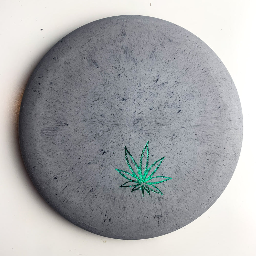 A round, gray stone coaster showcasing the iconic leaf design from Gateway's Wizard Leaf Suregrip Putters, displayed on a white background.