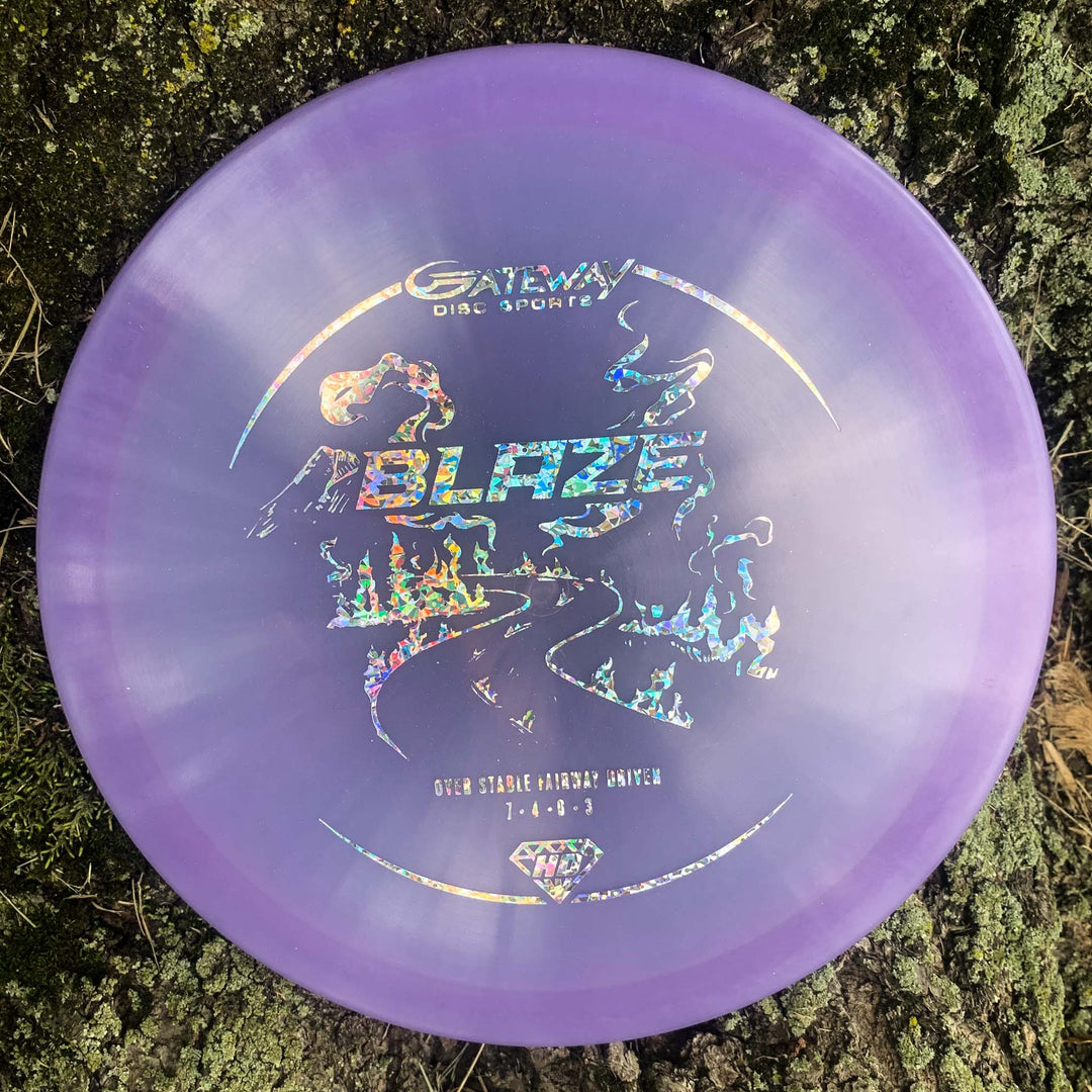 A purple Blaze - Hyper Diamond (HD) disc by Gateway Disc Sports with holographic art and text, pictured on mossy ground—an overstable driver ideal for reliable flights, even in headwinds.