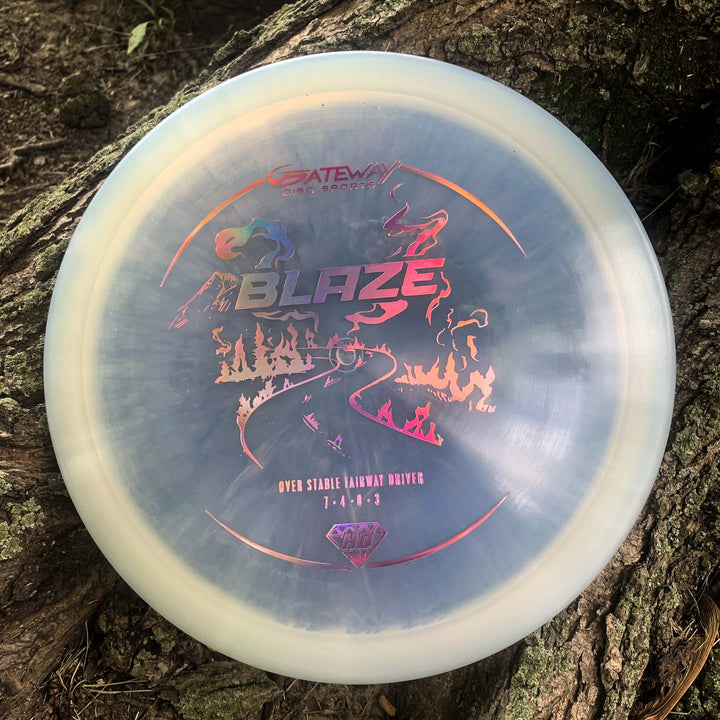 A Gateway Blaze - Hyper Diamond (HD) overstable driver with vibrant artwork and —Blaze—� plus —Over Stable Fairway Driver 7-4-1-3,—� rests on a tree trunk—ideal for predictable headwind drives.