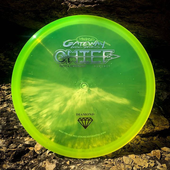A bright green Chief - Diamond putt & approach disc with a beaded rim from Gateway Disc Sports rests on a rough, textured rock surface.