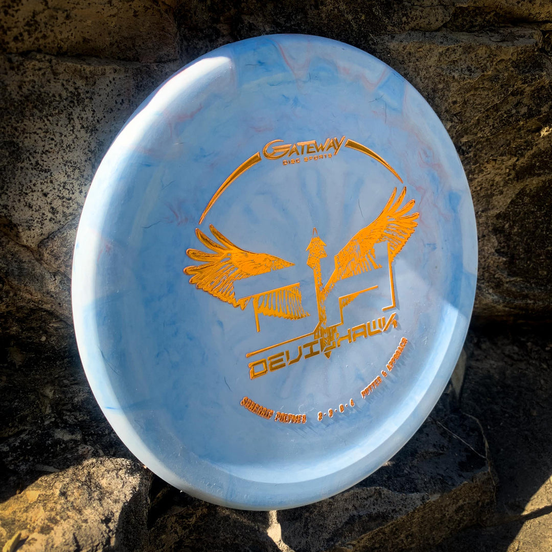 A light blue Devilhawk - SureGrip over-stable putter disc with a gold winged logo and "Gateway Disc Sports Devil Hawk" text rests against a rocky background.
