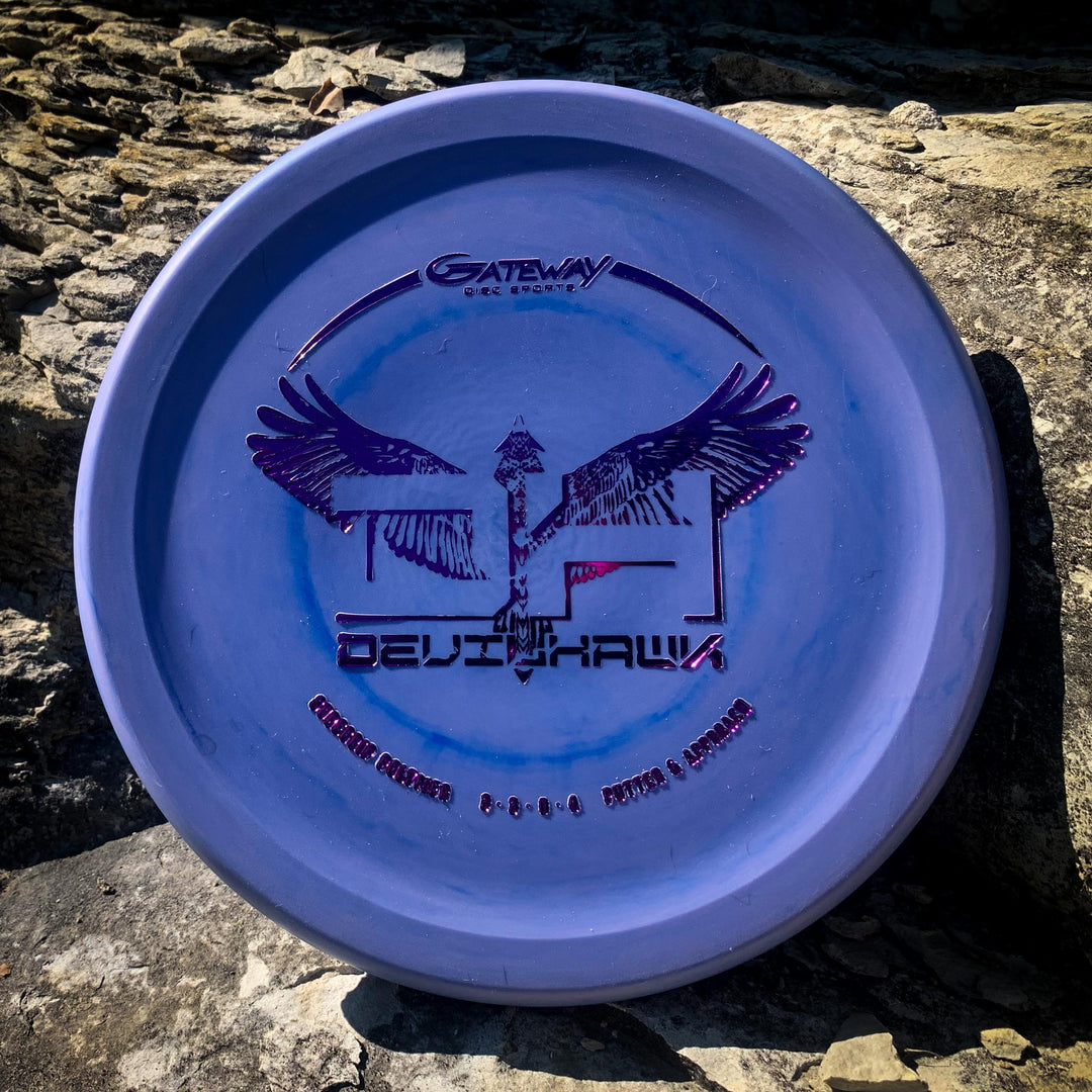 A purple Devilhawk - SureGrip over-stable putter with a winged logo and text rests on a sunlit, rocky surface.