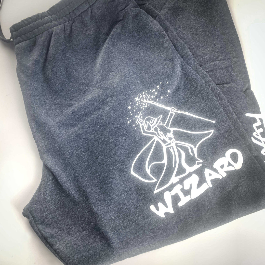 Gateway Joggers in dark gray fleece, showcasing a white graphic of a wizard casting magic with "WIZARD" printed below the illustration.