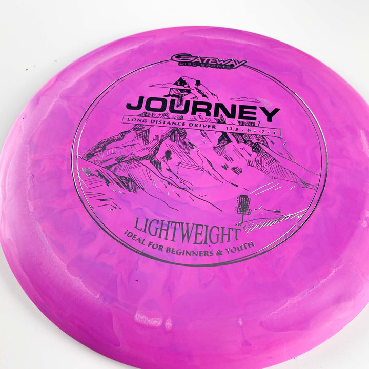 The Journey Lightweight - SureGrip is a pink long-range distance driver by Gateway Disc Sports, with black mountain graphics, offering lightweight, controllable flights—ideal for beginners and youth seeking maximum throw distance.