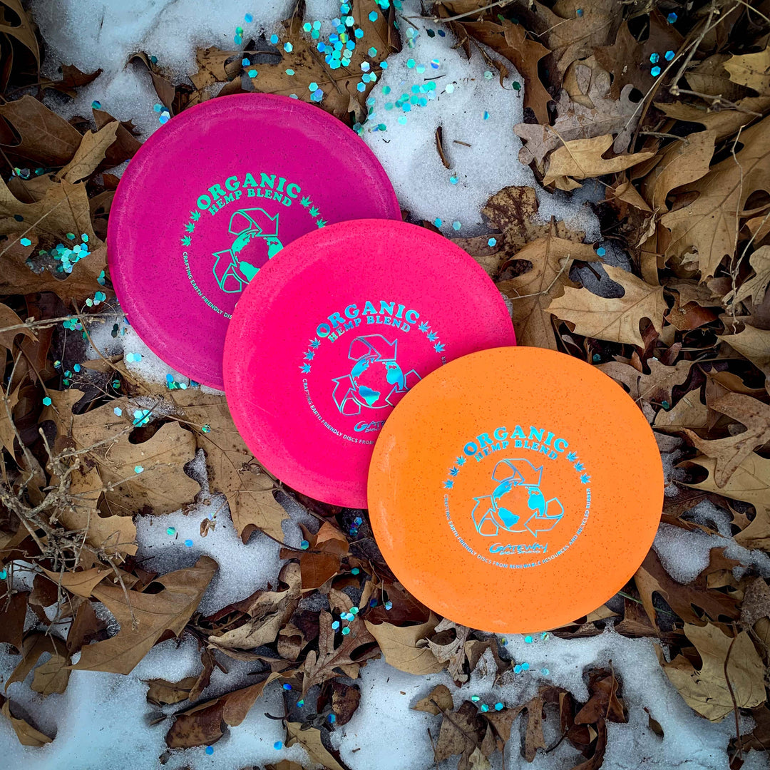 Three Prophecy - Suregrip Hemp discs rest on snowy ground among dry leaves and blue confetti, showcasing their quality hemp blend construction designed for reliable disc golf performance.