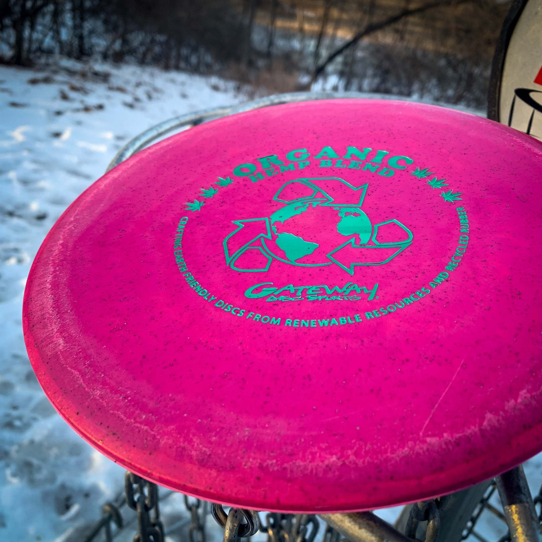 Close-up of the Prophecy - Suregrip Hemp disc by Gateway Disc Sports, labeled "Organic Hemp Blend," resting on a snowy metal basket; known for its consistent, overstable mid-range flight.