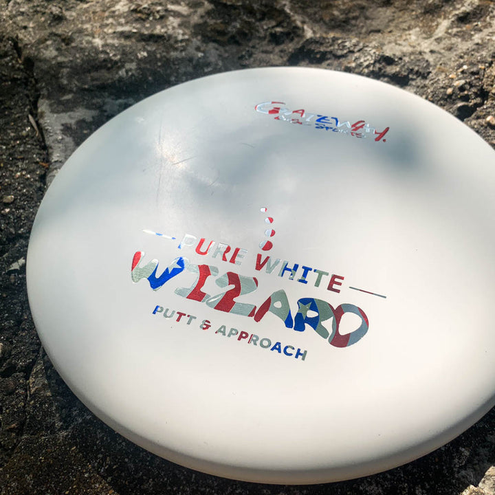 A Wizard - Pure White putter from Gateway rests on a textured outdoor surface—a reliable workhorse ideal for windy putting and approach shots.