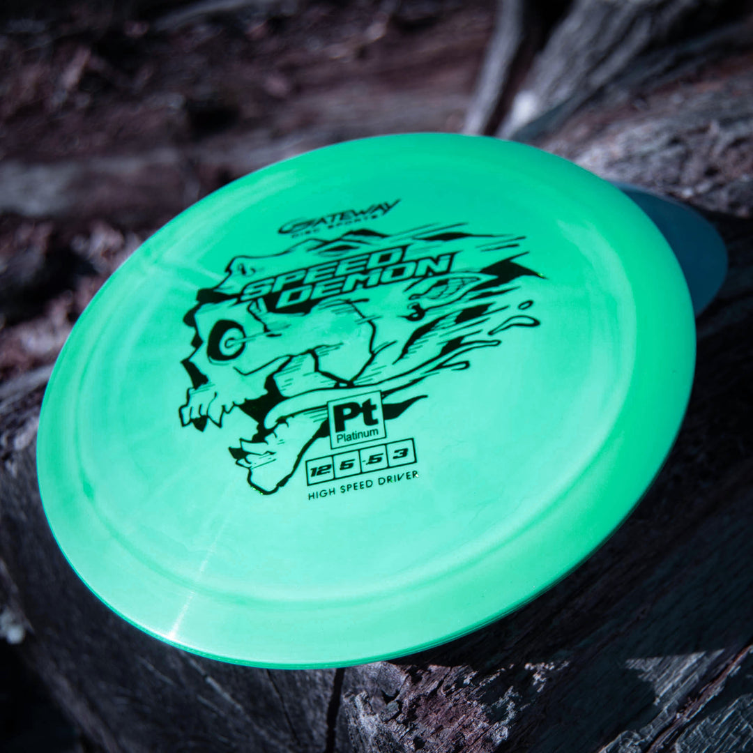 A green Speed Demon - Platinum overstable distance driver with a skull graphic rests on wood, ideal for power forehands or backhand flex shots.