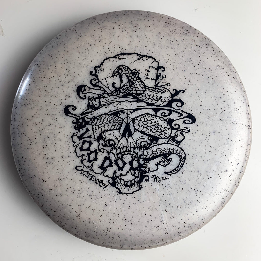The Voodoo - Diamond Hemp is a white disc golf putter with black speckles, featuring an intricate snake and skull-in-hat design—perfect for fans of distinctive putters.