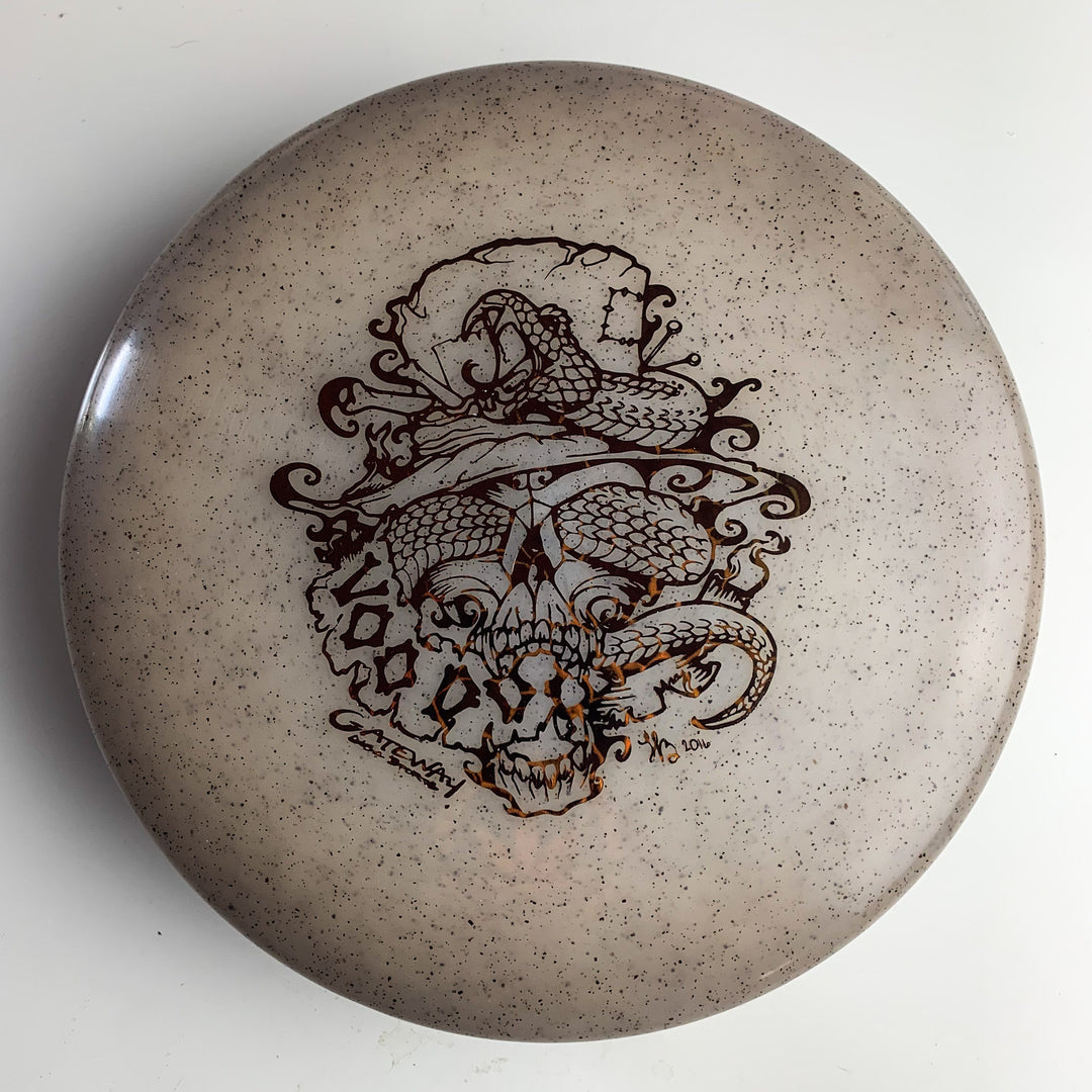 A tan Voodoo - Diamond Hemp putter disc golf disc featuring a detailed black illustration of a snake coiled around a top-hat-wearing skull.