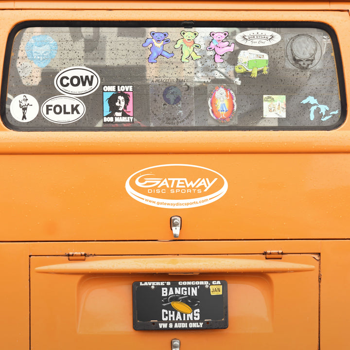 Rear of an orange van features a Gateway Disc Sports Team Window Decal, a white vinyl transfer sticker, various other stickers on the windows, and a "BANGIN' CHAINS" license plate with a January tag.