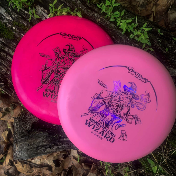 Two Wizard - Money putters, renowned for accuracy and stable performance, rest on a tree trunk among leaves—one in dark pink, the other light pink.